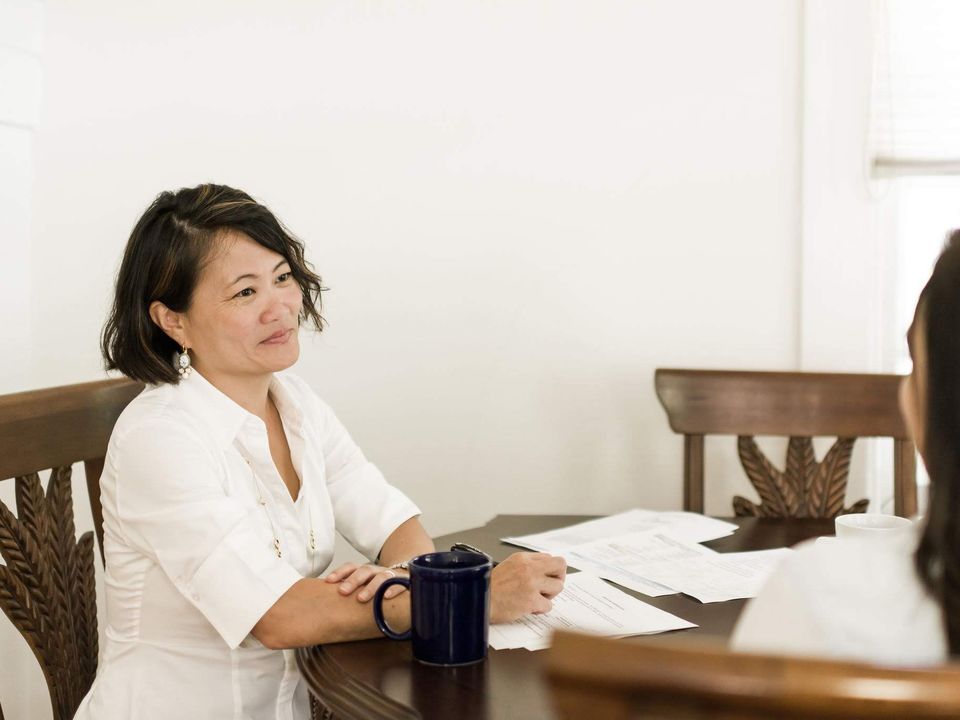 An in-person meeting at a table with printed plans and coffee